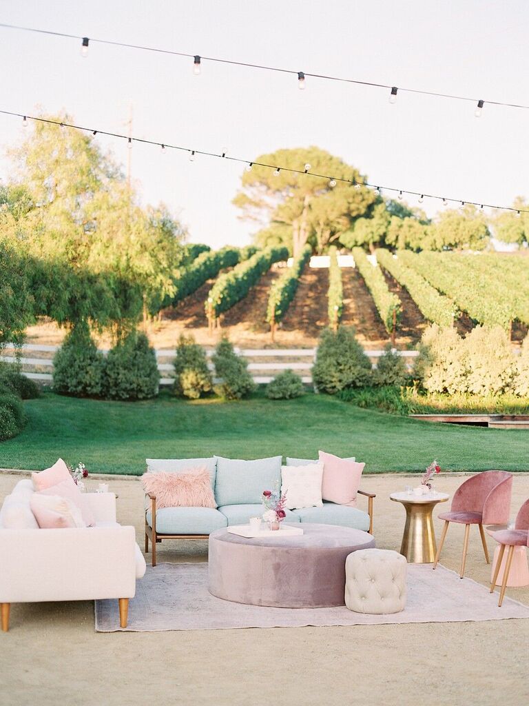 outdoor wedding reception with lounge area featuring pink, blue and lilac sofas and chairs