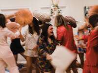 Women having pillow fight at bachelorette party sleepover