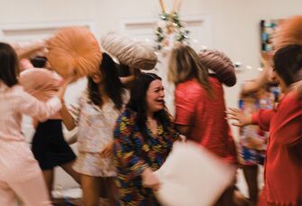 Women having pillow fight at bachelorette party sleepover