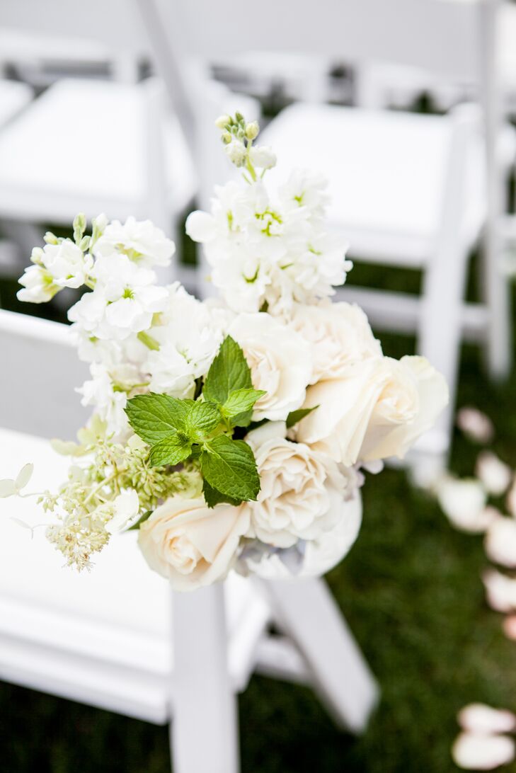 “I began with a secret garden theme,” Kelley says. “I wanted flowers everywhere and in various colors and sizes.” Their aisle helped to do just that with lush hanging arrangements. Ivory roses, white delphiniums and greenery in clear glass vases were placed against three rows of white chairs.
