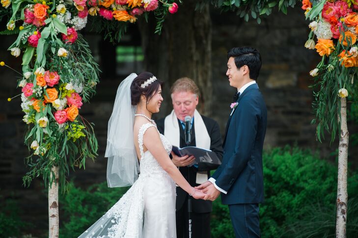 Paying tribute to the spring season, Alice and Stephen exchanged vows under a striking canopy of brilliant coral and orange garden roses, tulips, lush greenery and playful craspedia. The gorgeous garland adorned a birch structure, which mirrored the organic vibe of the natural setting.