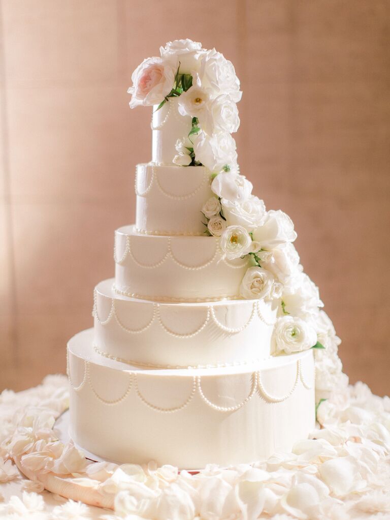 four tier elegant flower wedding cake with hand piped scallop pattern and ivory roses cascading down the side