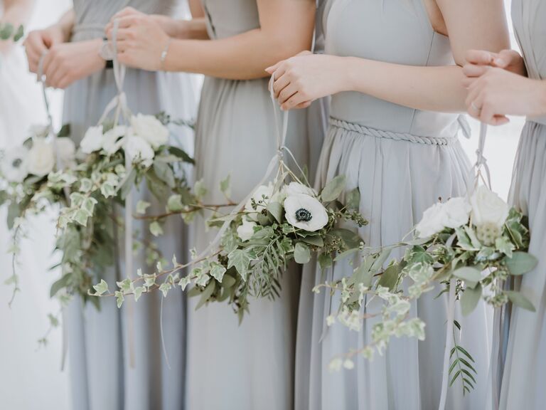 Bridesmaids hold these pale white and green bouquets.