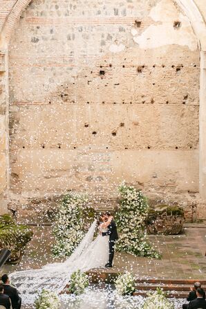 Bride and Groom Kissing at Altar in Guatemalan Ruins, White Flower Petals Falling