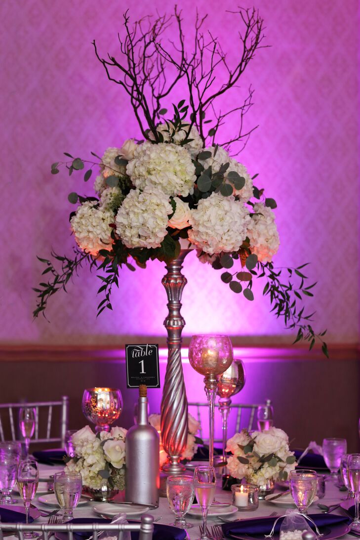 During the dinner reception, tall arrangements of white hydrangeas and sculptural branches were paired with gold decor and purple uplighting.