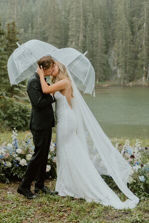 Bride and Groom Kiss Under Umbrellas at Rainy Outdoor Ceremony, Wildflowers and Lakeside