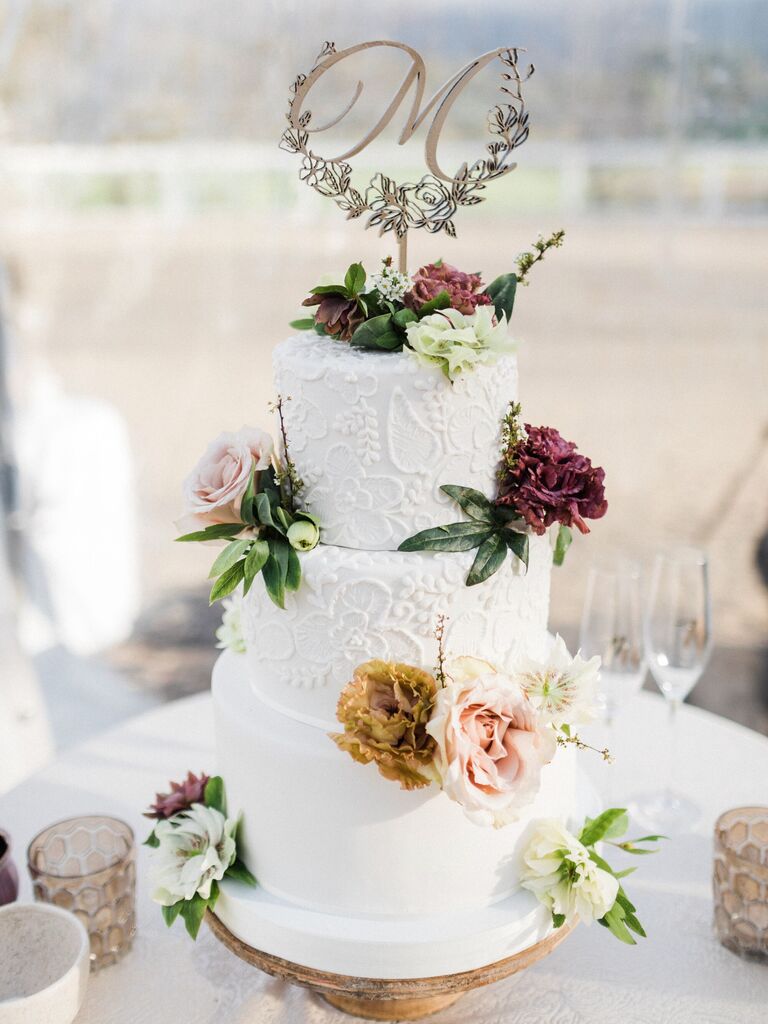 white fall wedding cake with hand-piped icing in floral design and fresh flower accents