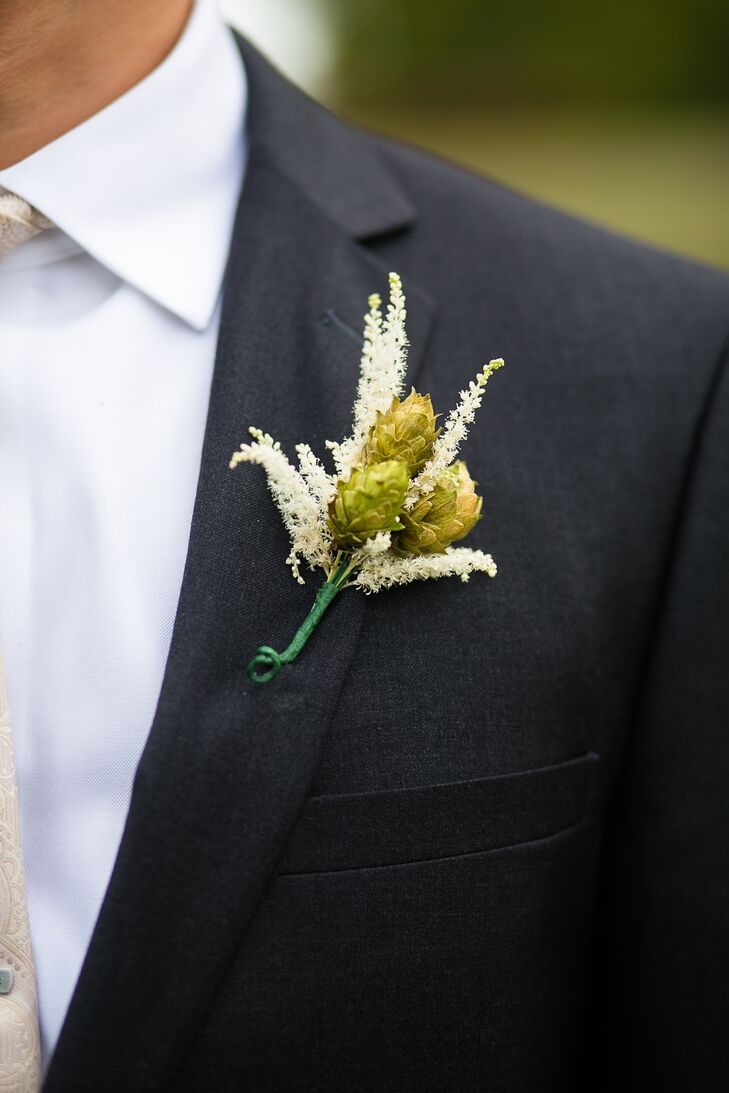 Mike and his groomsmen dressed for the wedding in gray suits paired with white shirts and brown shoes. To complement the farm setting, each man also added a whimsical touch to his attire. All wore fun boutonnieres of green hops surrounded by white astilbes and tied with green ribbon.