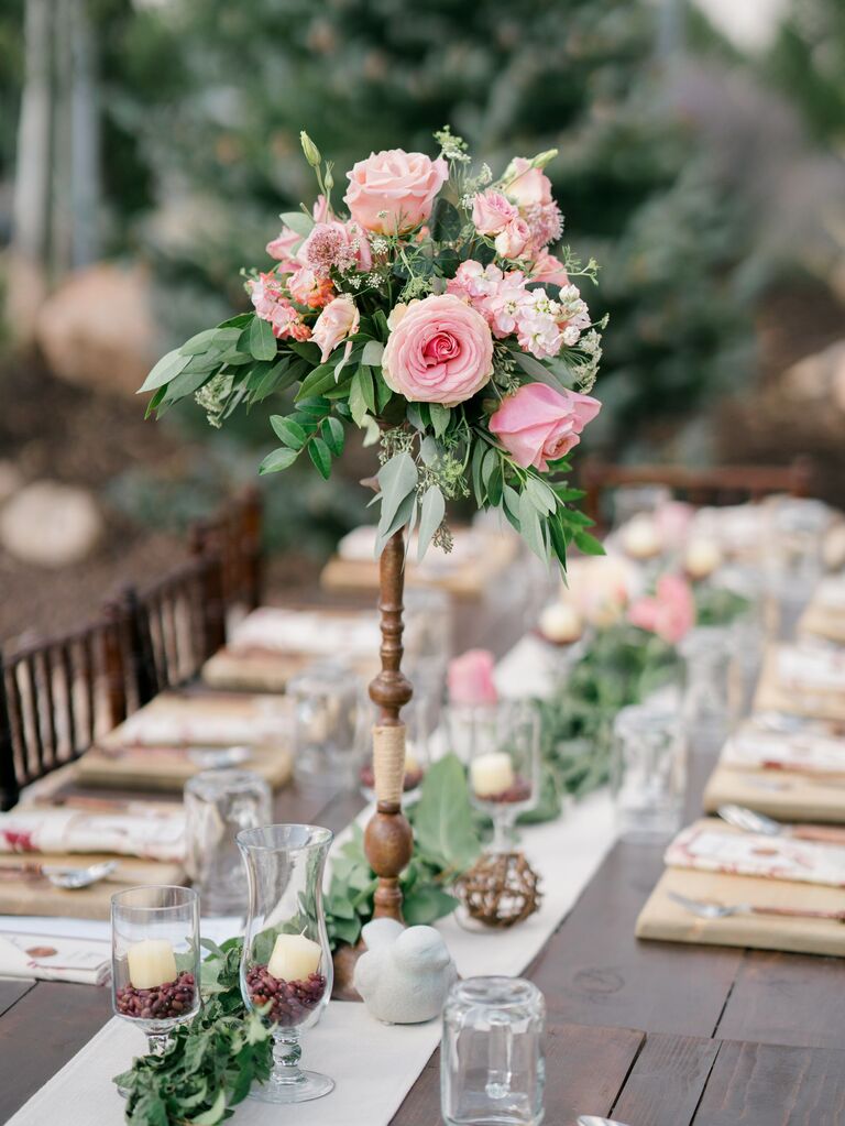 tall wedding centerpiece with small cluster of pink roses and eucalyptus on wooden pedestal