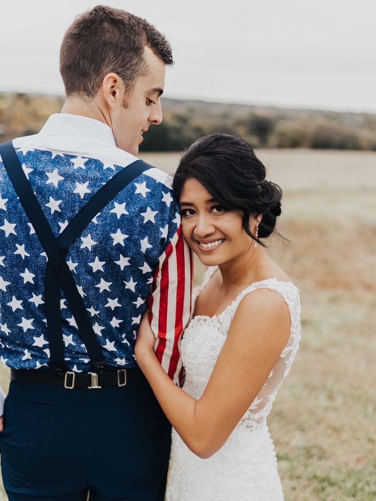 bride leans against groom's shoulder wearing american flag printed dress shirt with suspenders