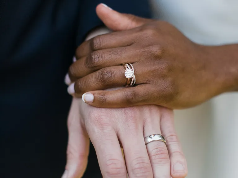 Couple holding hands wearing engagement ring and wedding bands