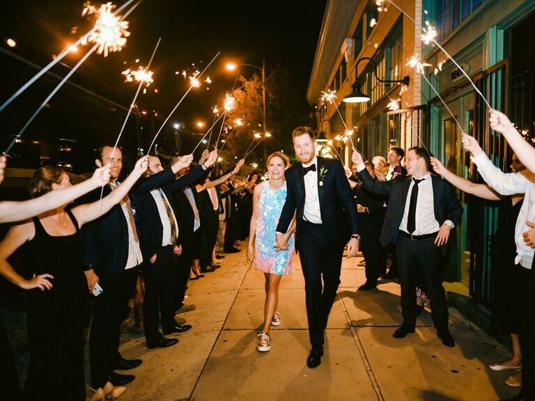 Bride and groom exiting wedding reception under sparkler tunnel