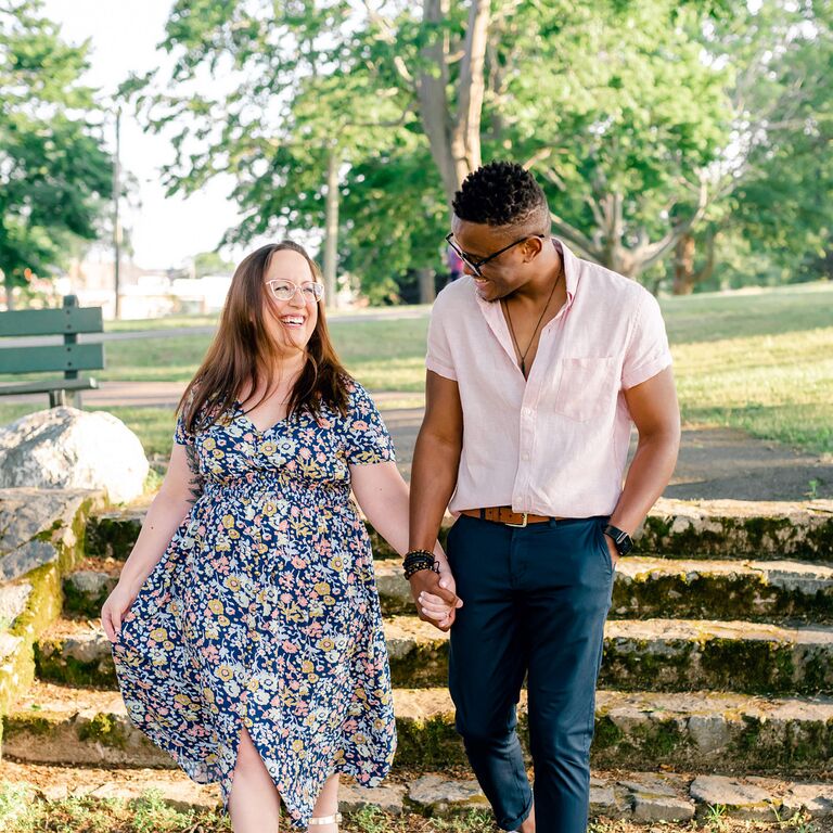 Couple walks hand-in-hand through park during sunset engagement photo shoot