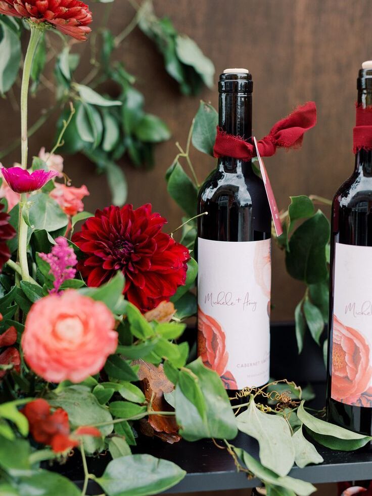 Custom wine bottle with escort card tag surrounded by flowers