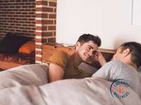 two men lying in bed and talking