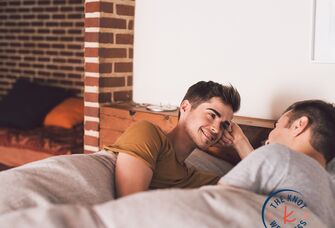 two men lying in bed and talking