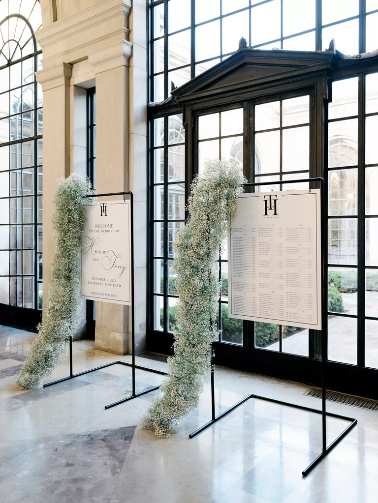 Baby's breath arrangements cascade down this modern wedding signage.