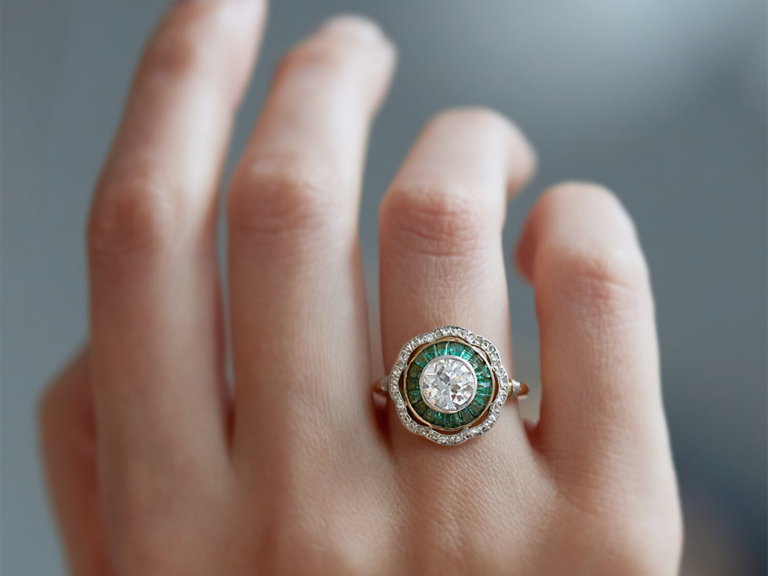 Circle cut diamond bordered by emerald and floral glass stone halo