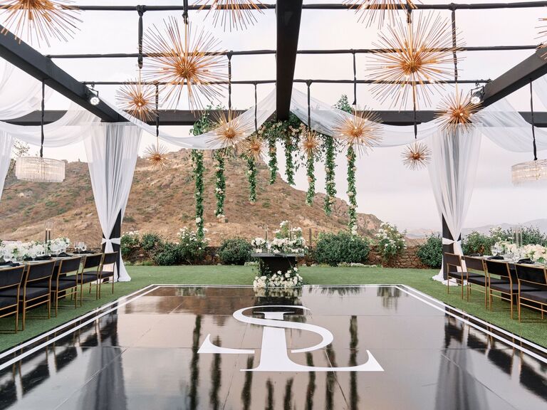 Monogrammed dance floor with starburst chandeliers overhead. 