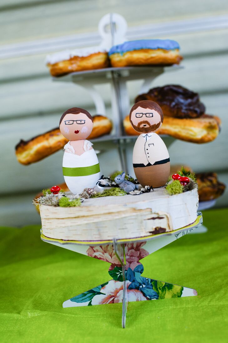The wedding cake was designed to look like it was covered with bark on the surface. The cake topper had two wood figurines that resembled Melissa and Carl dressed in their wedding day attire. Little animal figurines and natural accents also decorated the top. The dessert was positioned on top of a paper stand decorated with a flower design.