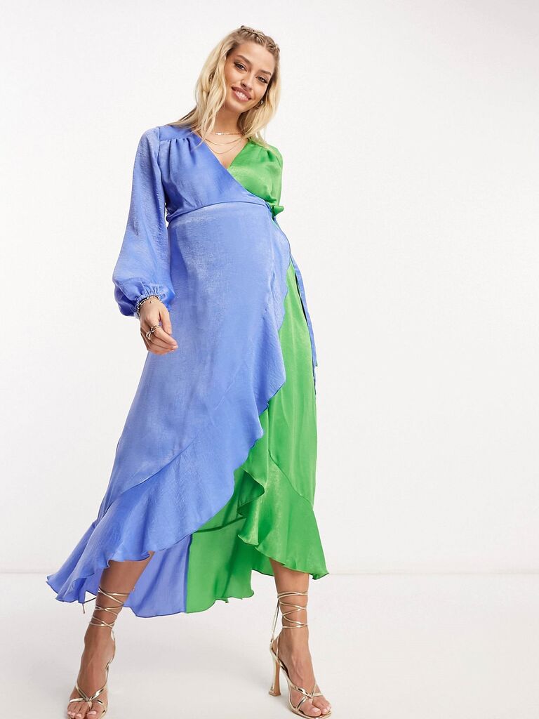 Model wears a green and blue ruffled gown. 