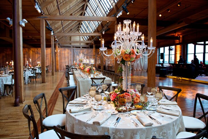 “Our centerpieces brought a distinctly floral and romantic element to the Bridgeport Air Center space,” says Brielle. Tables covered in champagne linens hosted bountiful, vibrant coral and peach flowers and greenery in low vases or tall crystal candelabras, and were covered with candles and tea lights to exude romance.