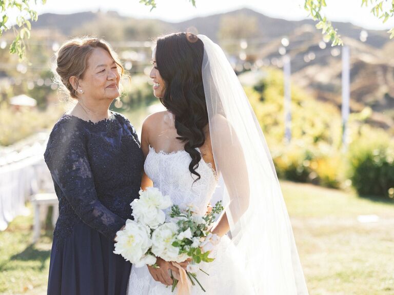 Bride and her mother smile at each other on the wedding day. 