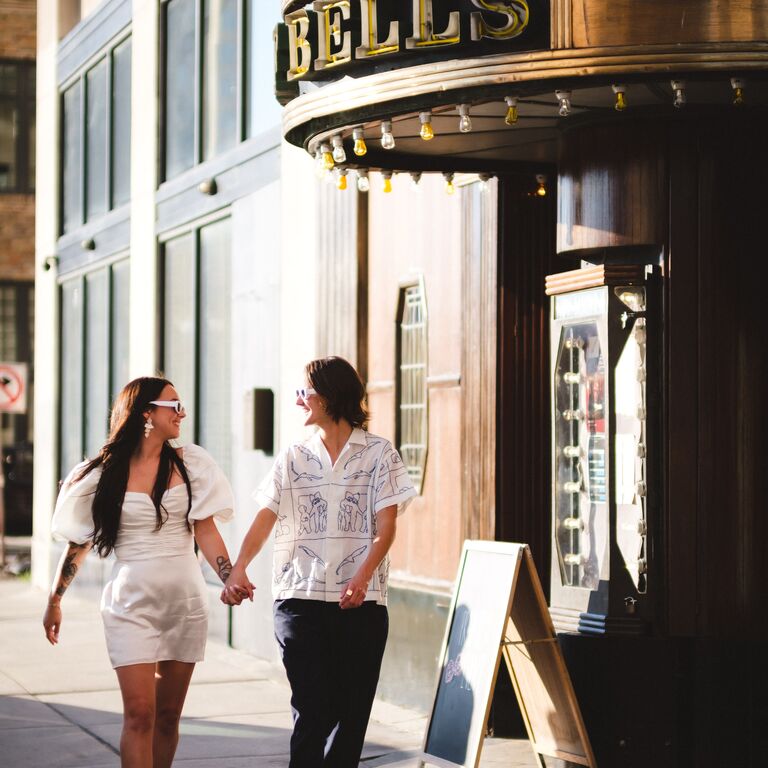 Modern engagement photo walking hand-in-hand down the street
