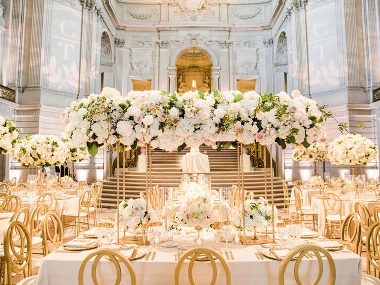 Lavish regency-inspired wedding reception with towering floral centerpieces and gold chairs