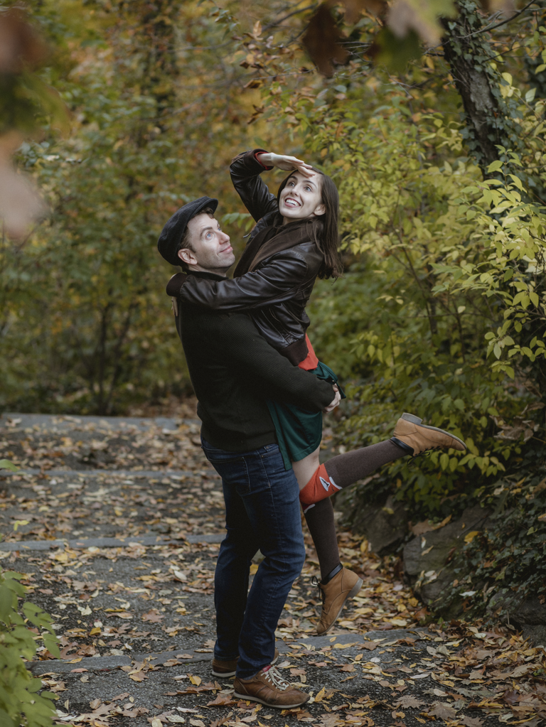 Couple poses like explorers in the woods at their engagement shoot. 