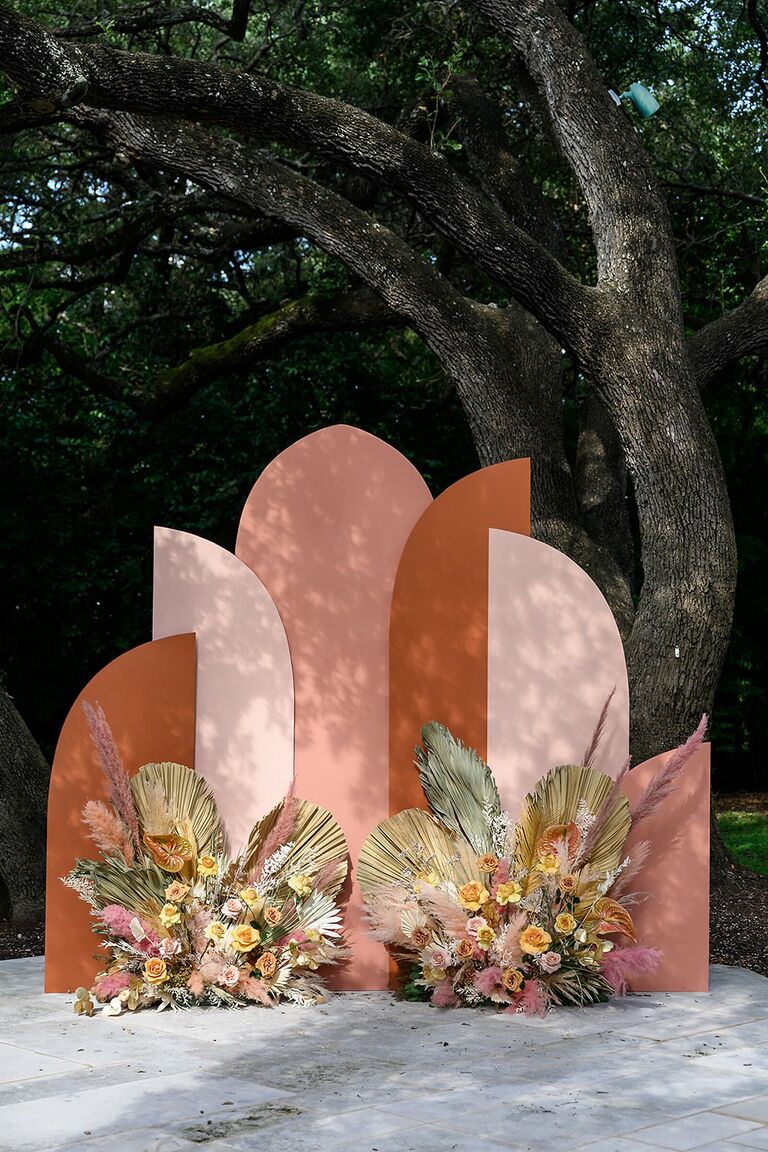 arched boho wedding ceremony backdrop with 2022 wedding colors rust, beige and blush pink