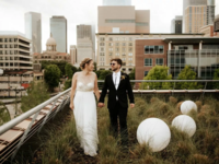Bride and Groom Take a Stroll Through the Grass at Sunset Coffee Building wedding venue in Houston, Texas