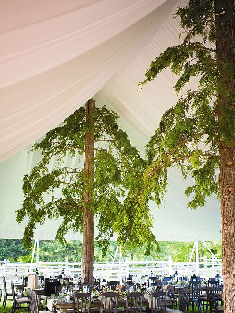 Tree-inspired wedding tent pole covers with thick green leaves