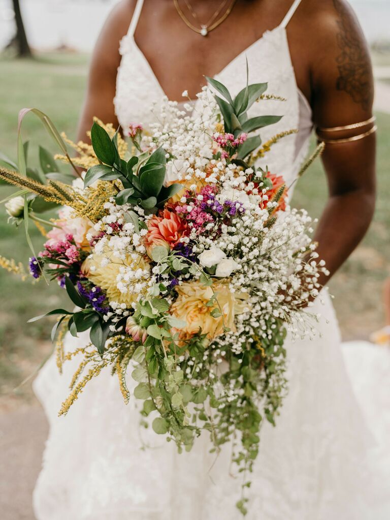 Bride holding bouquet of wild flowers and baby's breath for summer wedding