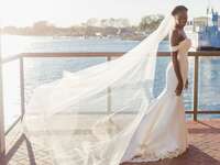 Bride wearing off-the-shoulder wedding dress with cathedral-length veil
