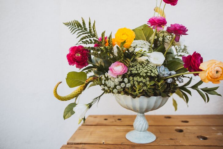 The reception was decorated with arrangements filled with fern leaves, Queen Anne's lace, colorful ranunculus and lush succulents. The assorted greens and flowers were arranged inside elegant white vases, arranged by Lavender and Clove.