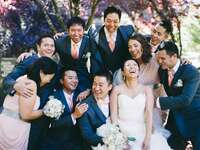 Mismatched wedding party with more groomsmen than bridesmaids laughing together with the bride and groom.