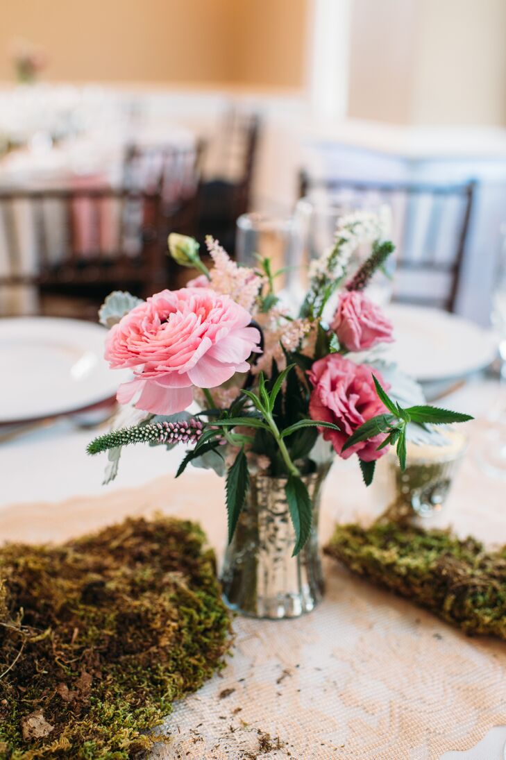 Of course, their pink wedding color also popped against the reception decor. Ibranyi Is Floral marked their tables with bunches of moss alongside mercury vases with pink ranunculus, astilbes, lisianthus and veronica. Wisps of added greenery and dusty miller broke up the display for a more natural look.