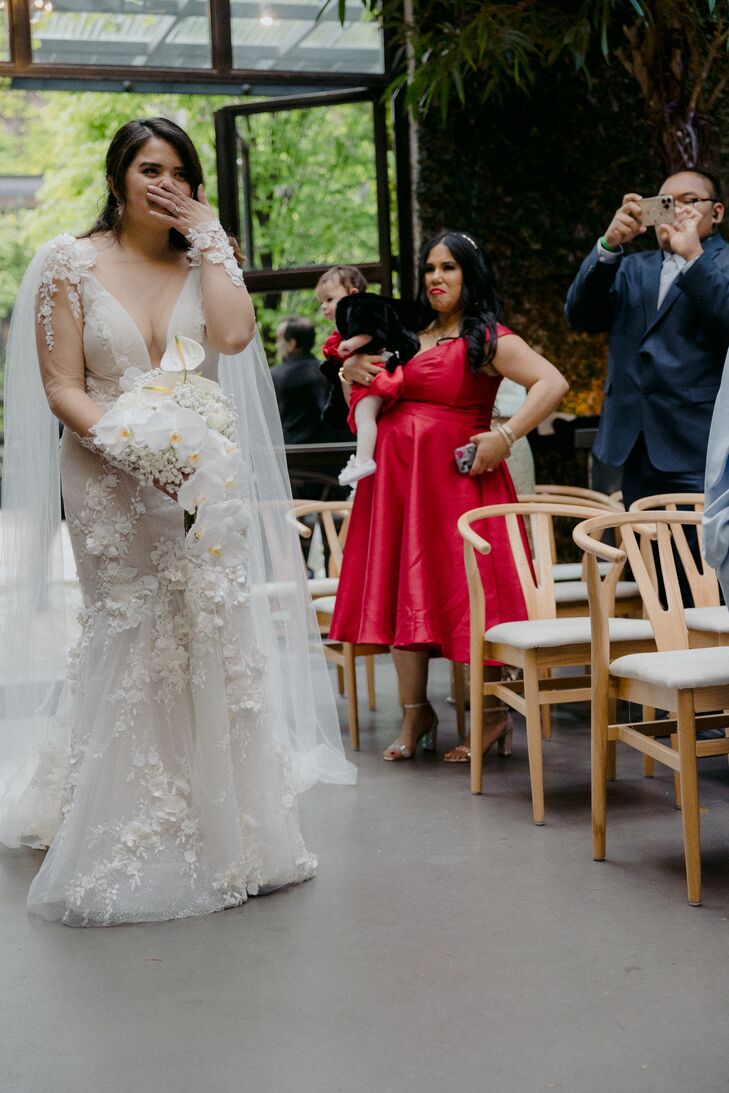 Bride in Fitted Gown, Cape and White Bouquet Walking Down the Aisle Holding Back Tears