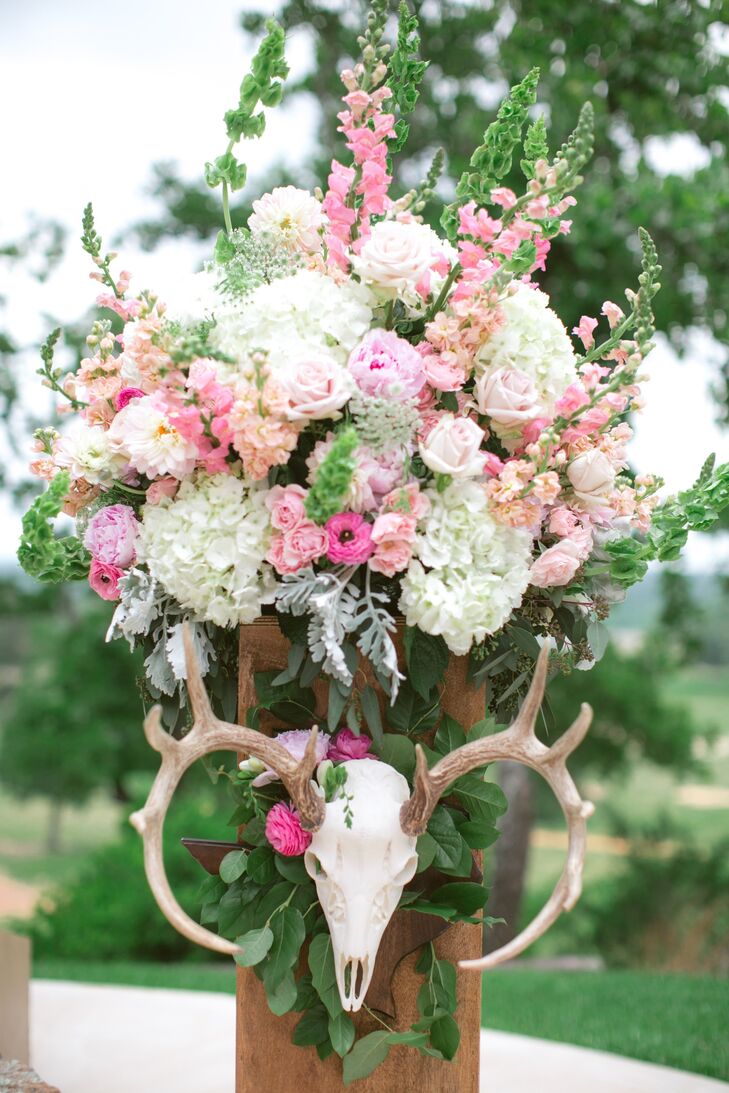 Arrangements of ivory, pink and peach blossoms decorated the pillars on either side of the ceremony altar. The finishing touch --- an deer skull placed on each to tie into the day's rustic, ranch theme.