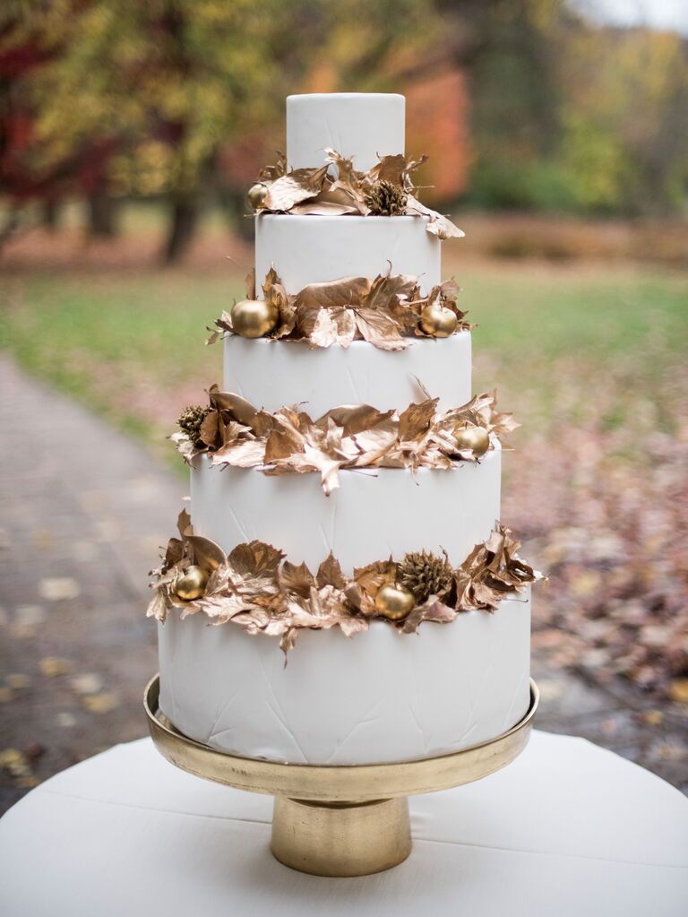 four-tier fall wedding cake with gold leaves in between each tier