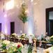 Inside the reception space, guests sat at dark wood dining tables set with gold plates and decorated with a green grass runner. A variety of moss, candles and colorful flower centerpieces covered the surface.