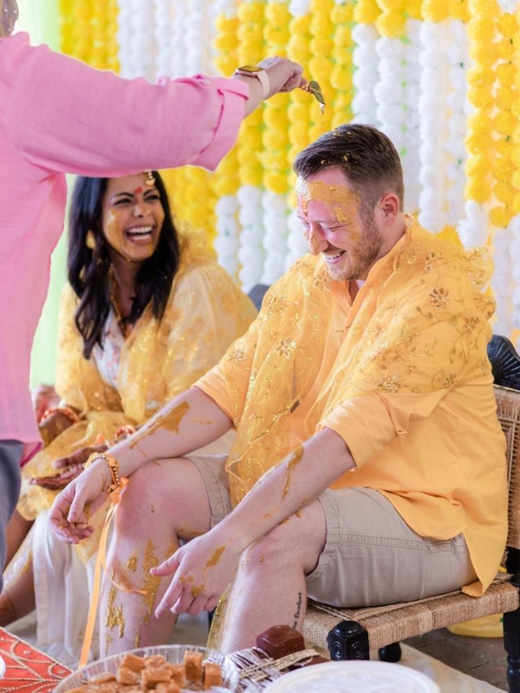bride and groom covered in turmeric paste at pithi ceremony