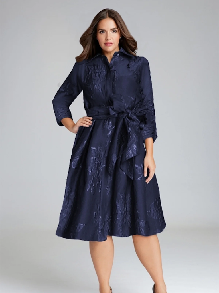 A model wears this navy shirt dress with a glamorous bow at the natural waist.