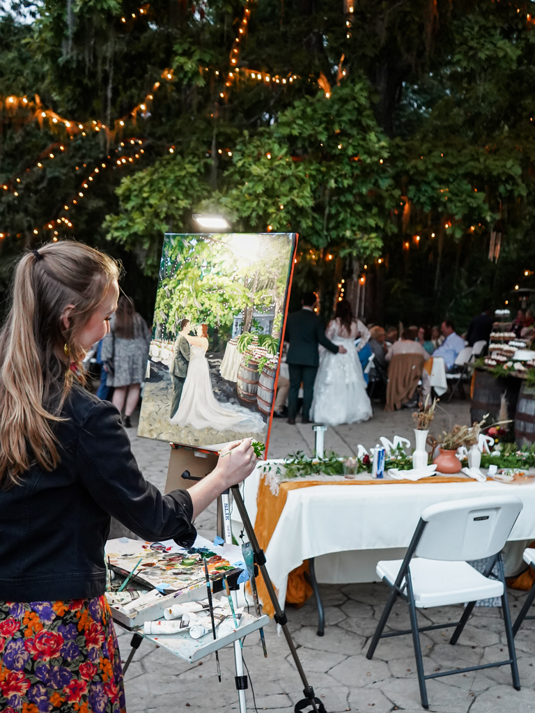 Live painter works on a romantic scene of the newlyweds in a sweet embrace. 