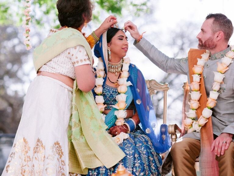 groom applying sindoor to bride's head during Hindu wedding ceremony