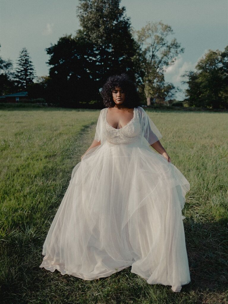 Model wears a romantic white gown with a pull skirt and fluttering sleeves. 