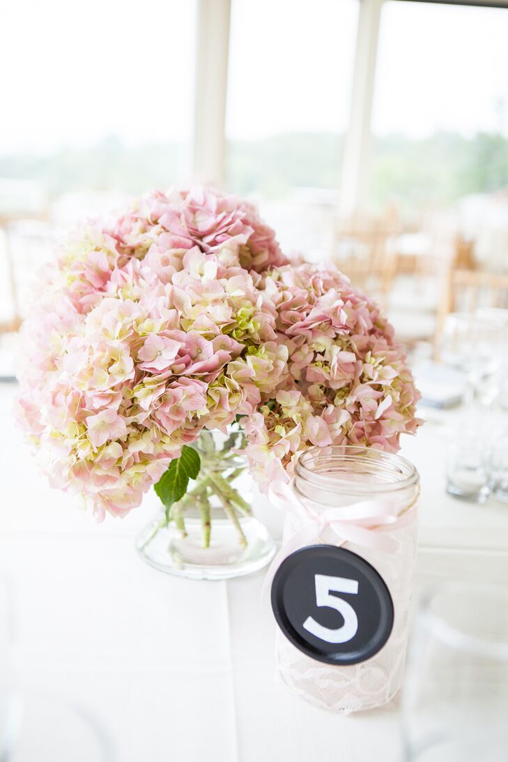 “I wanted a soft color scheme inside to go with the mountain view,” Kelley says. Each table was paired with a low arrangement of pink and green hydrangeas, which ensured that it wouldn’t obstruct their guests' views. The table numbers were placed nearby on clear glass jars wrapped in light pink lace.