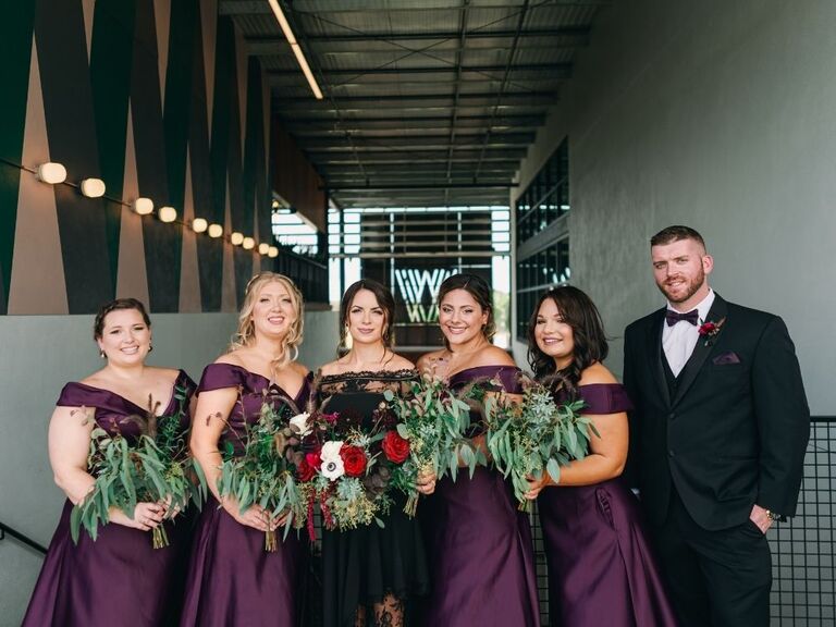 bride posing with bridesman and bridesmaids in purple attire