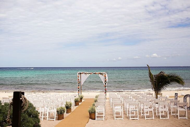 Marta and Jose Luis exchanged their vows on the beach under this linen-draped wedding arch. Potted greenery lined the aisle.